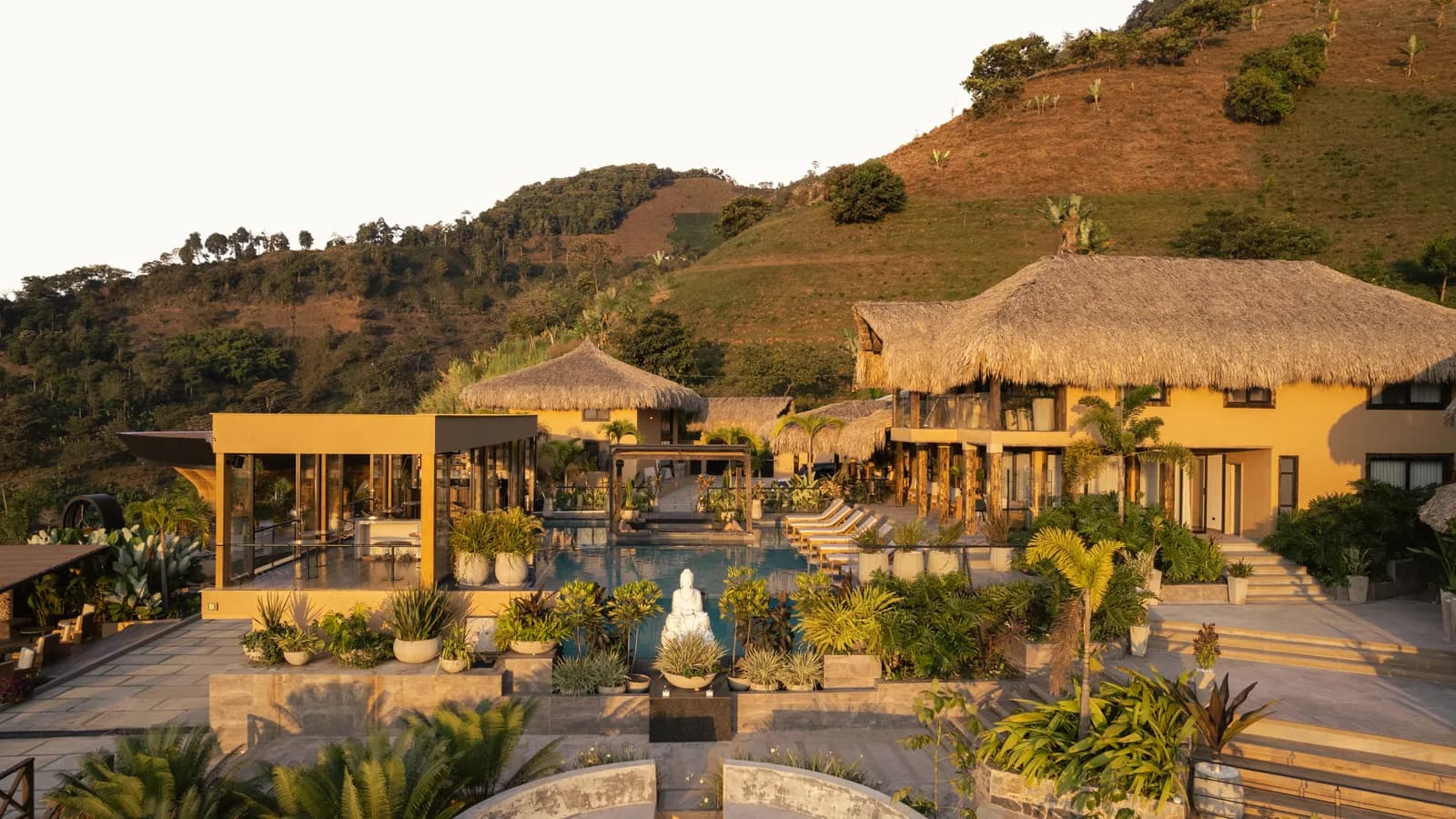 Casa principal con techo de palma, piscina y jardín al pie de la montaña